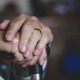 The hands of an older adult holding the top of a cane.