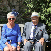 Two older adults dressed up and smiling.