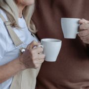 A photo of two people holding cups of coffee with their arms around each other